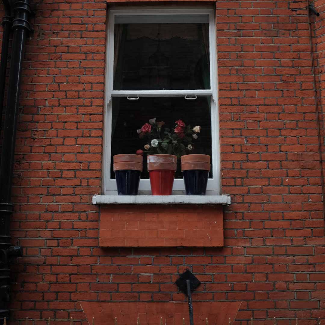 Ventana con macetas sobre pared de ladrillo