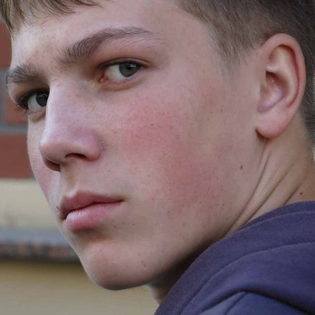 Retrato de perfil junto a una pared de ladrillo